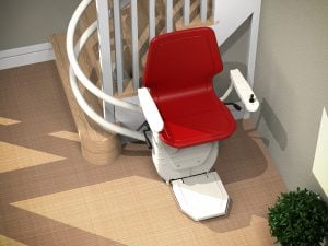 Curved red stairlift at bottom of wooden stairs