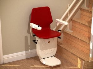 Red stairlift at bottom of wooden stairs